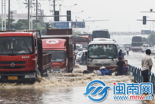 南環(huán)路上積水太深，摩托車在路中拋錨，市民躲上隔離欄