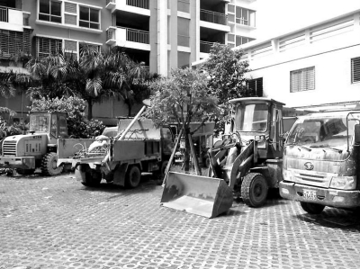 多輛工程車停放在小區(qū)公共綠化帶。