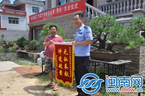 黃先生為民警送來錦旗，背后是黑松盆栽