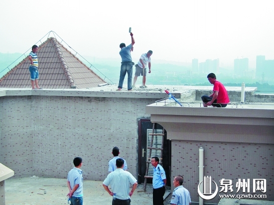 執(zhí)法人員組織工人對(duì)高層樓頂?shù)倪`法建筑進(jìn)行拆除