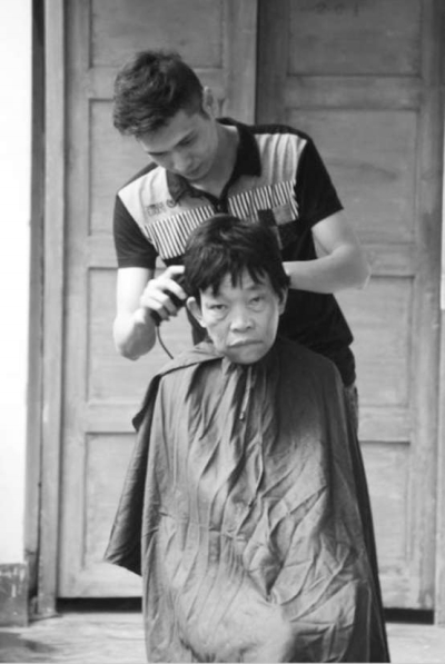 梁江華正在給老人理發(fā)。